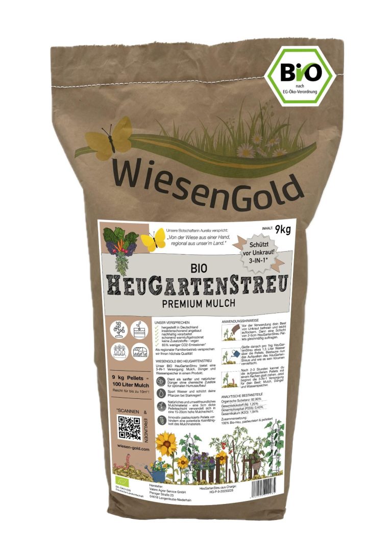 Mann verteilt HeuGartenStreu im Garten als Unkrautmulch, um Unkraut zu bekämpfen und Wasser zu sparen.